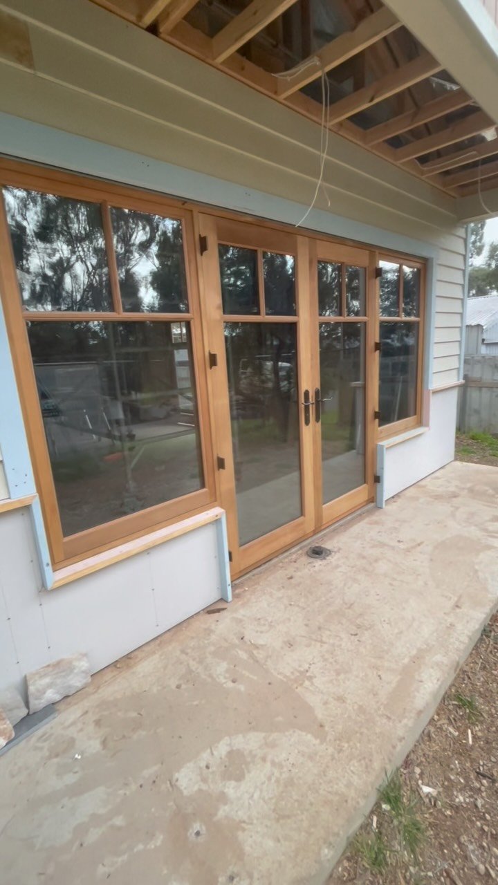 Cedar-toned French entry doors flanked by multi-pane windows on a home extension
