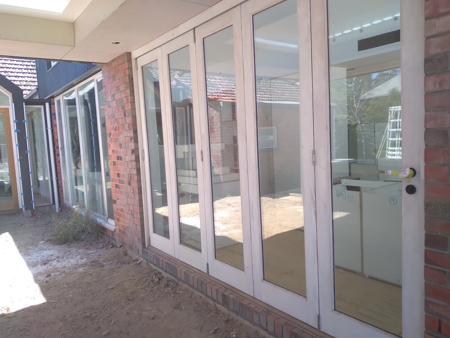 Primed timber four-panel bifold door, unfinished, opening onto a timber deck