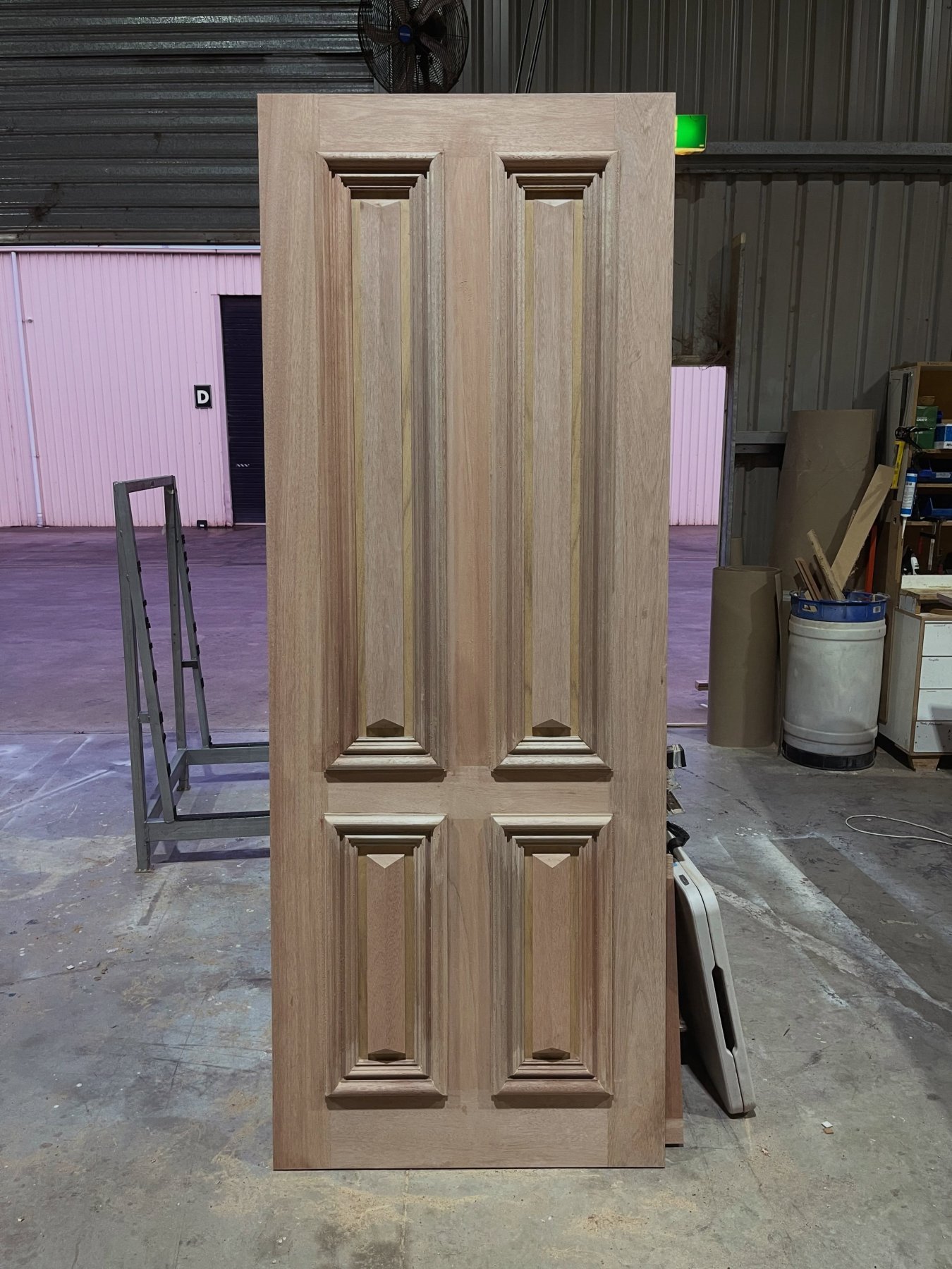 Four-panel raised timber entry door, unfinished, standing in the workshop