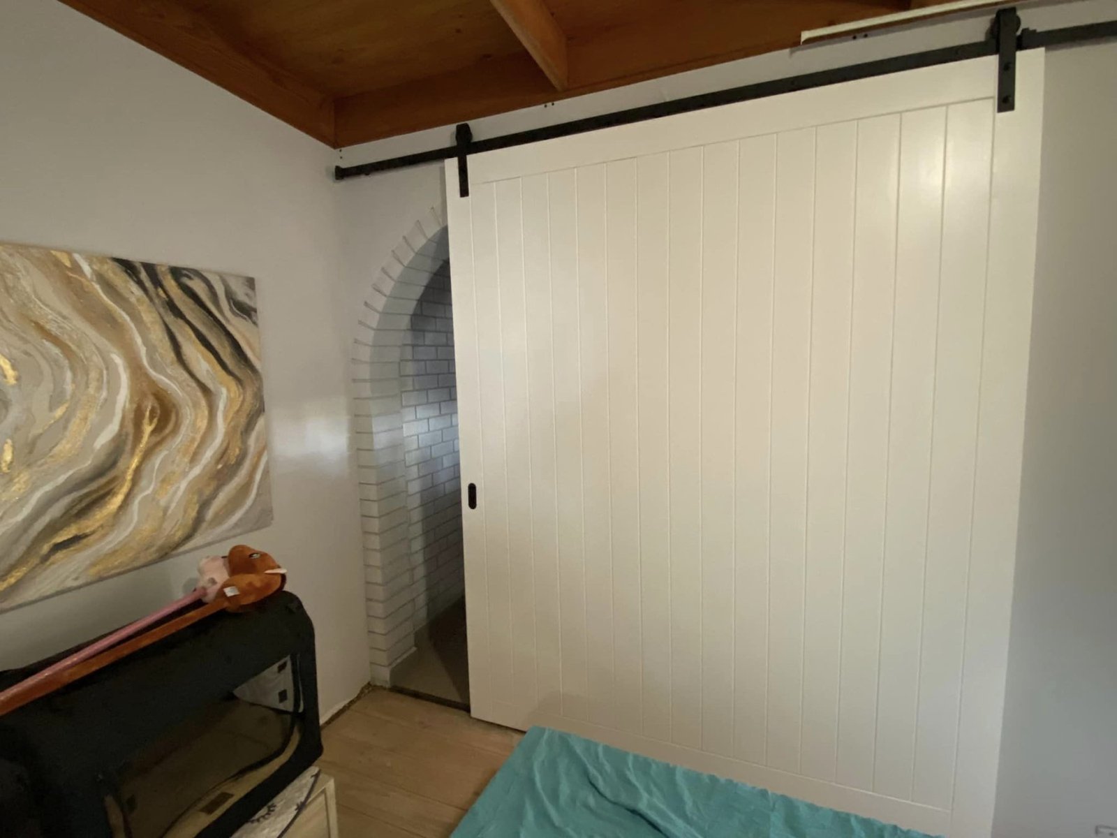 White painted sliding barn door with vertical panelling, opening onto an archway