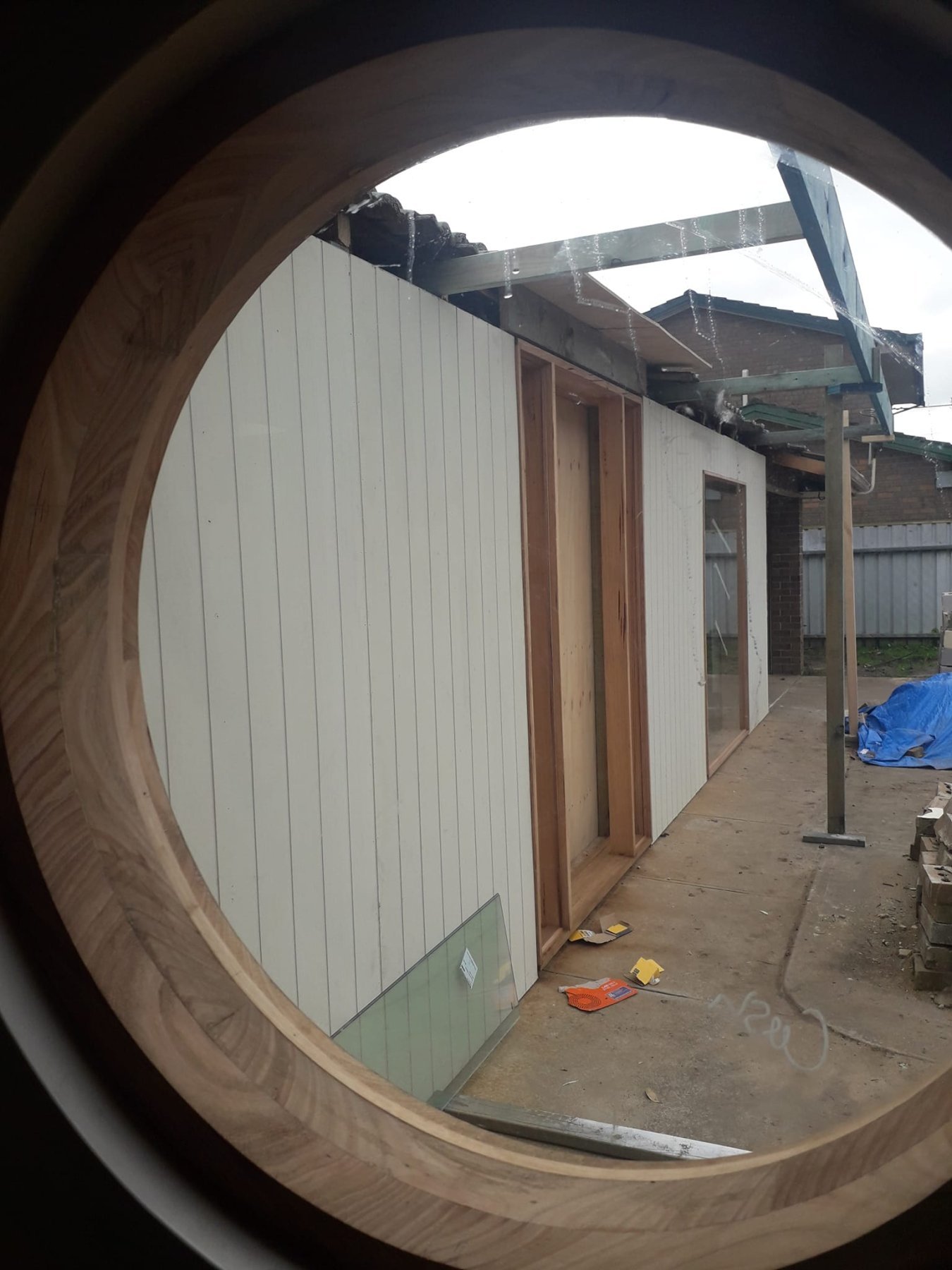 Vic Ash round porthole window installed in a garden studio wall