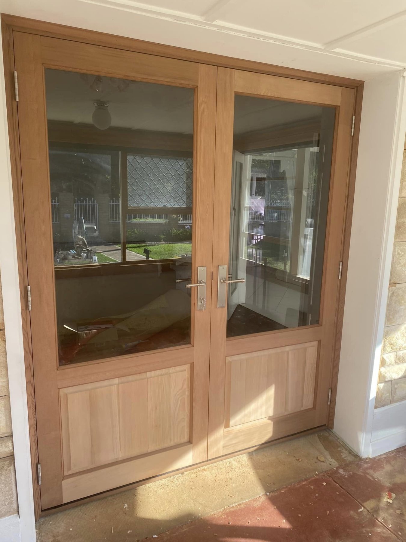 Cedar-toned timber double entry doors with glazed upper panels and brushed nickel hardware