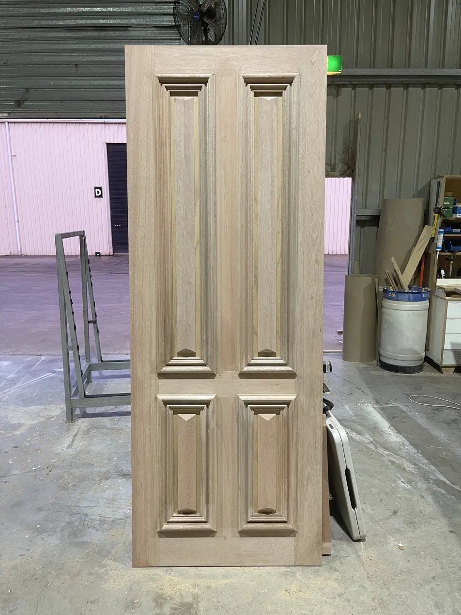 Four-panel raised timber entry door, unstained, ready for finishing in the workshop