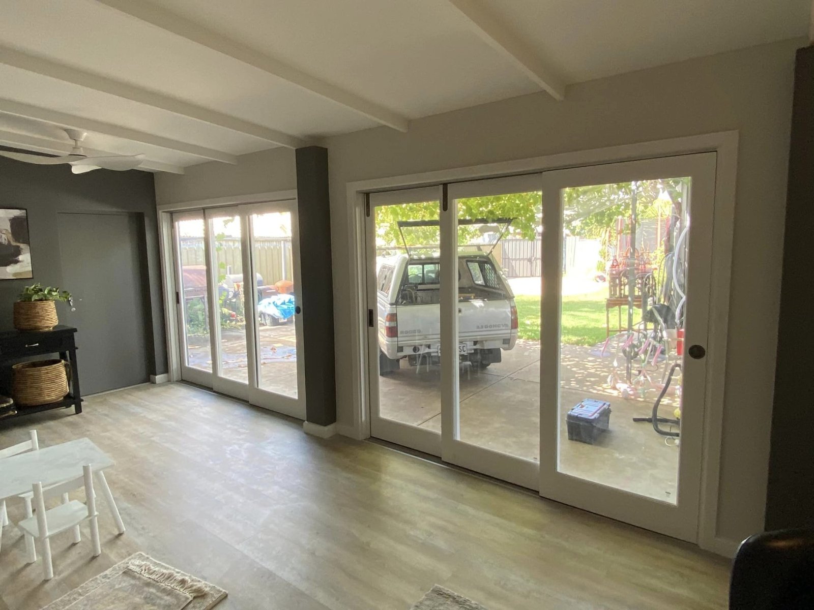 White-framed sliding door system opening onto a paved outdoor entertaining area