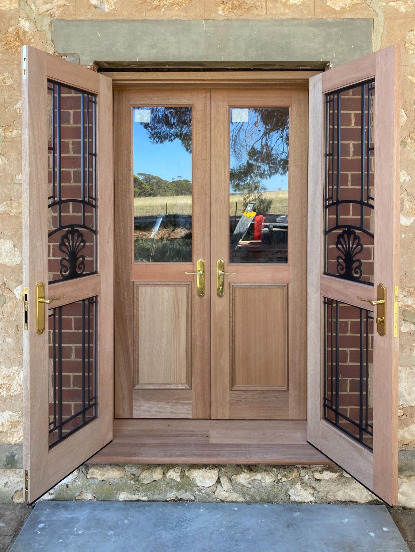 Timber double entry door with wrought-iron glazed sidelights and brass hardware