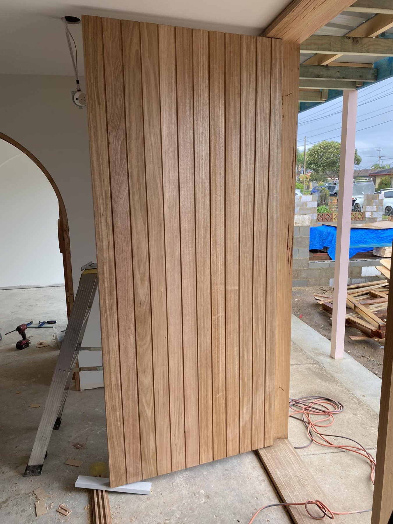 Vertical-shiplap timber door installed on a home extension, opening onto the patio