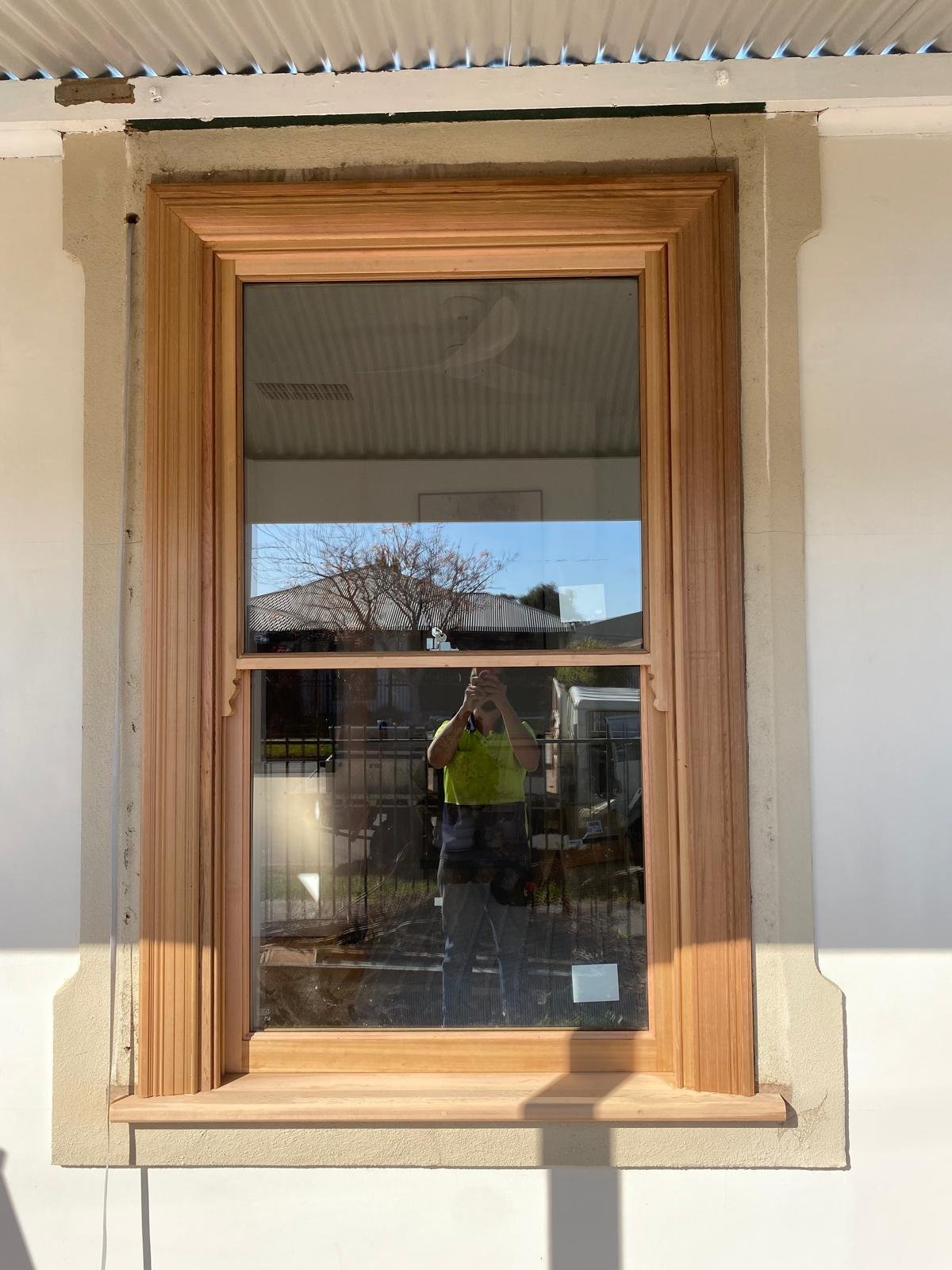 Ornate timber double-hung sash window with decorative corbels, heritage restoration