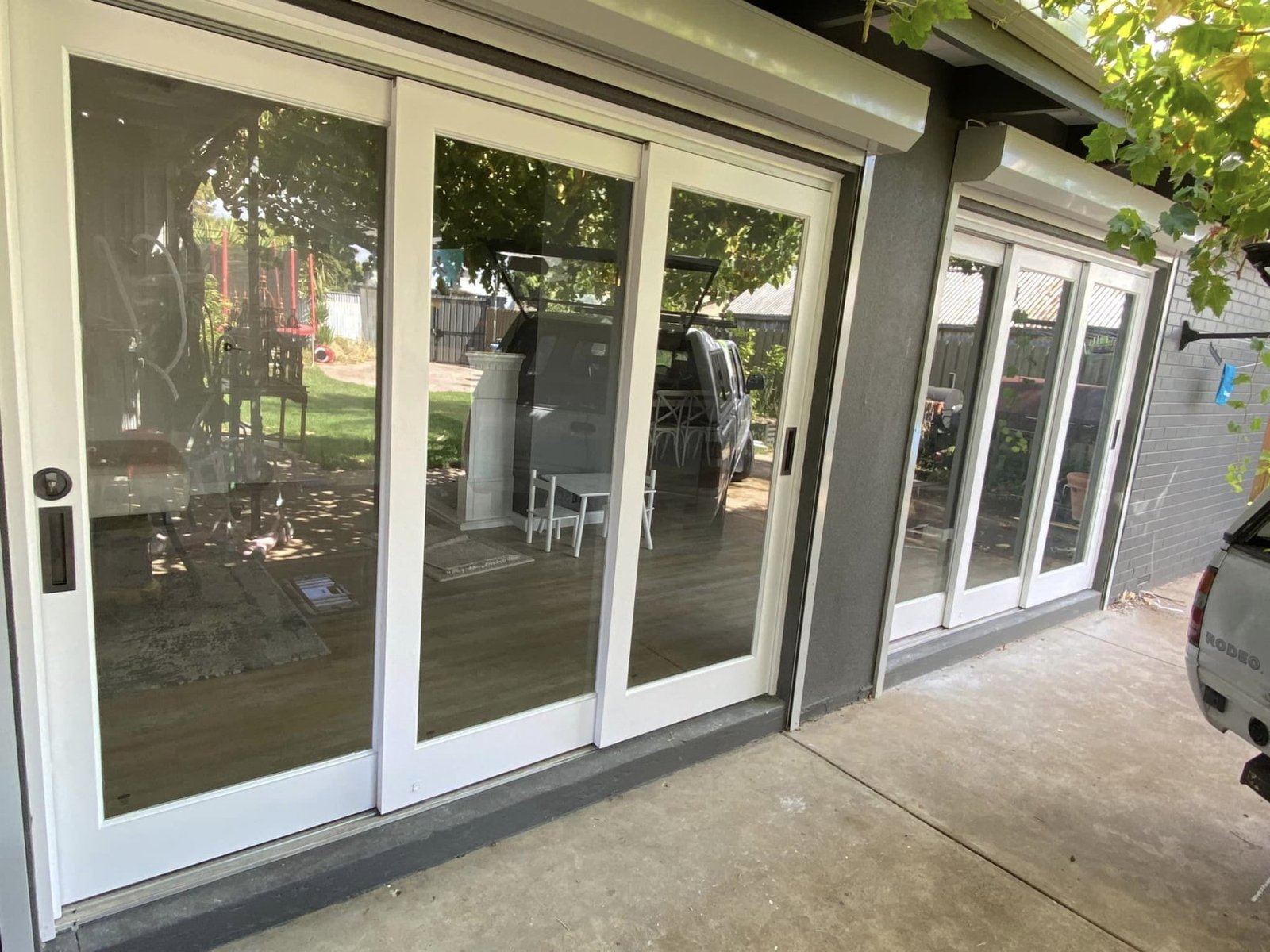 Sliding door open from a living room to a vine-covered outdoor patio