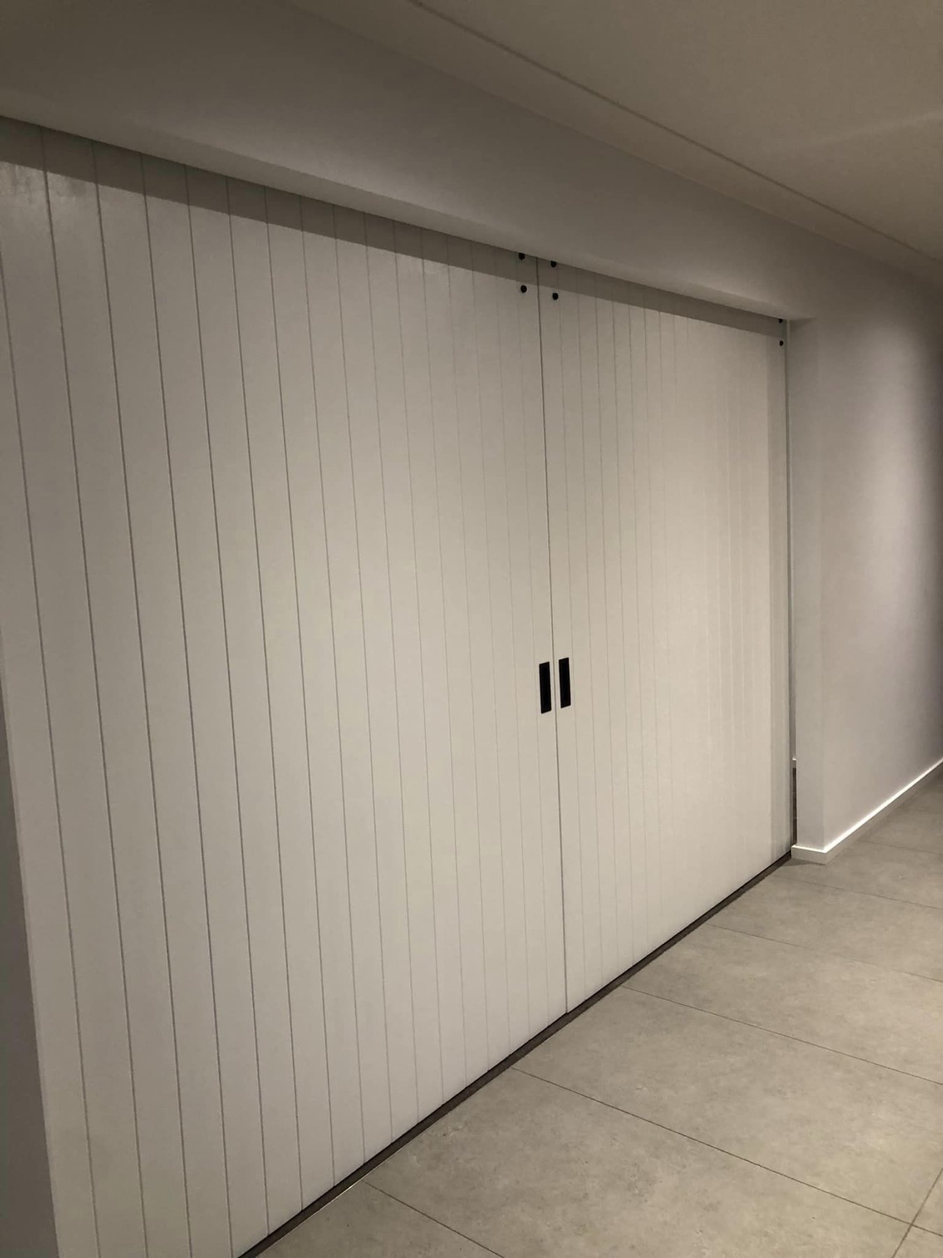 Wide white VJ-panelled sliding door concealing a walk-in storage space off the hallway, alternate angle