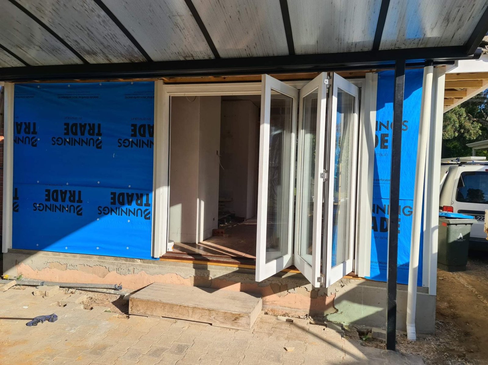 White-painted timber bifold door installed on a sunroom addition under construction