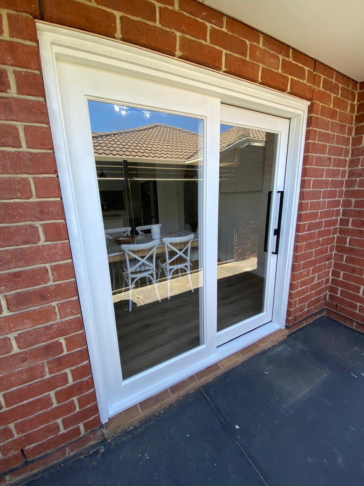 White-framed sliding glass door installed on a brick home patio
