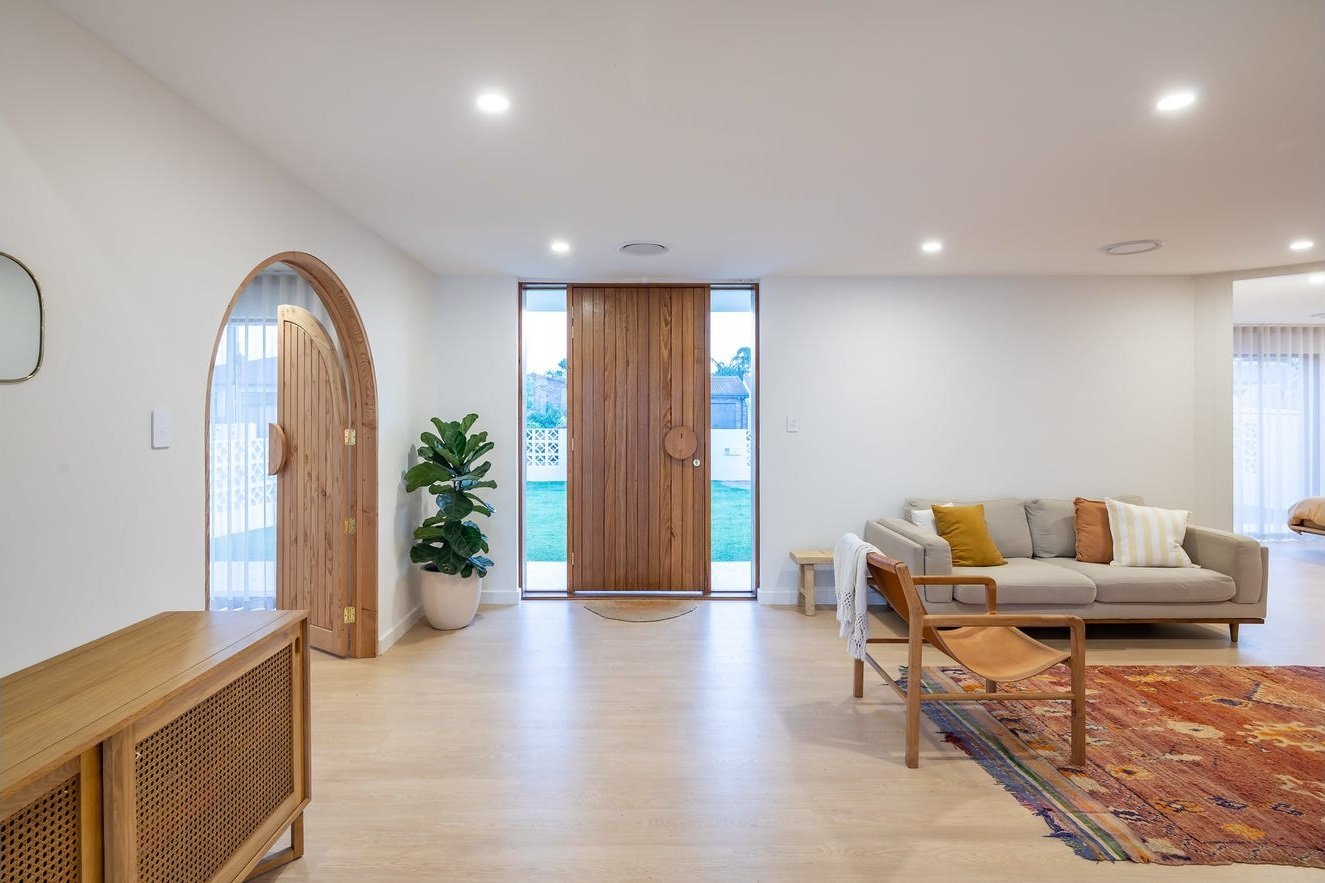 Modern timber entry door with a matching arched pivot door feature, interior view