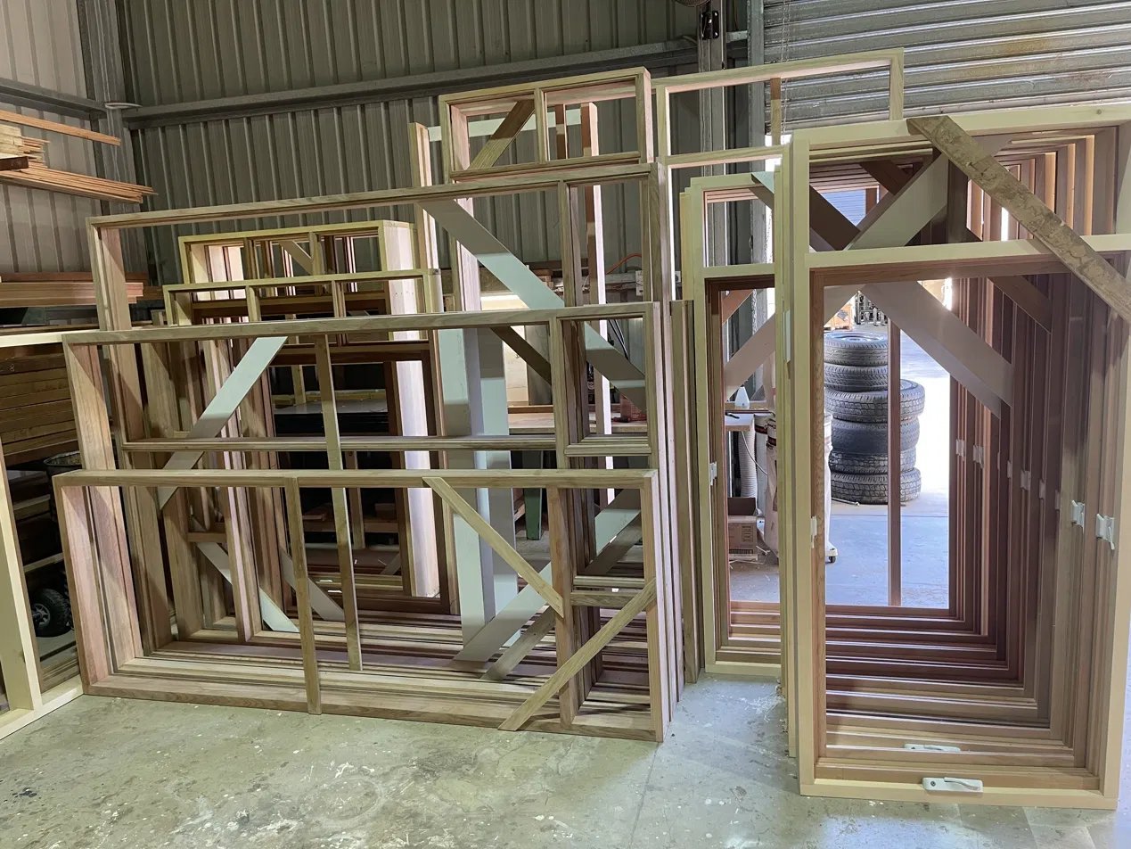 Timber window and door frames under construction, stacked in the workshop