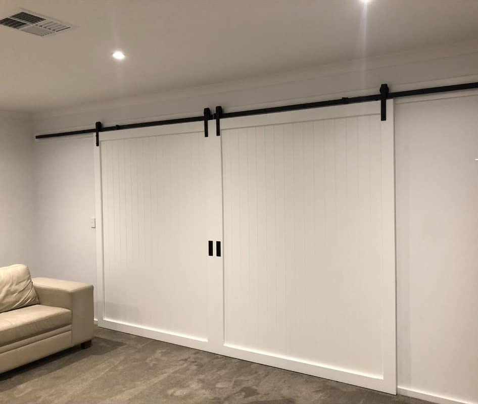 White vertical-panel sliding barn doors on black rail track, living room