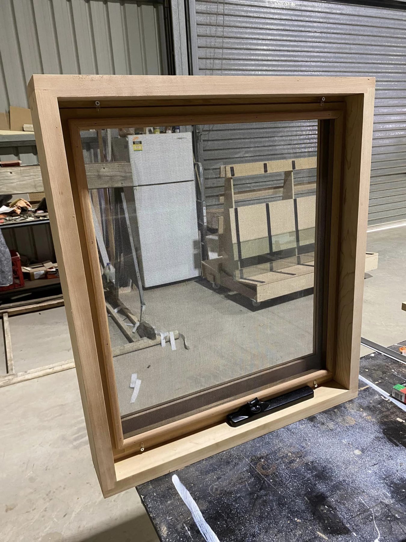 Western Red Cedar awning window with black hardware latch, workshop closeup