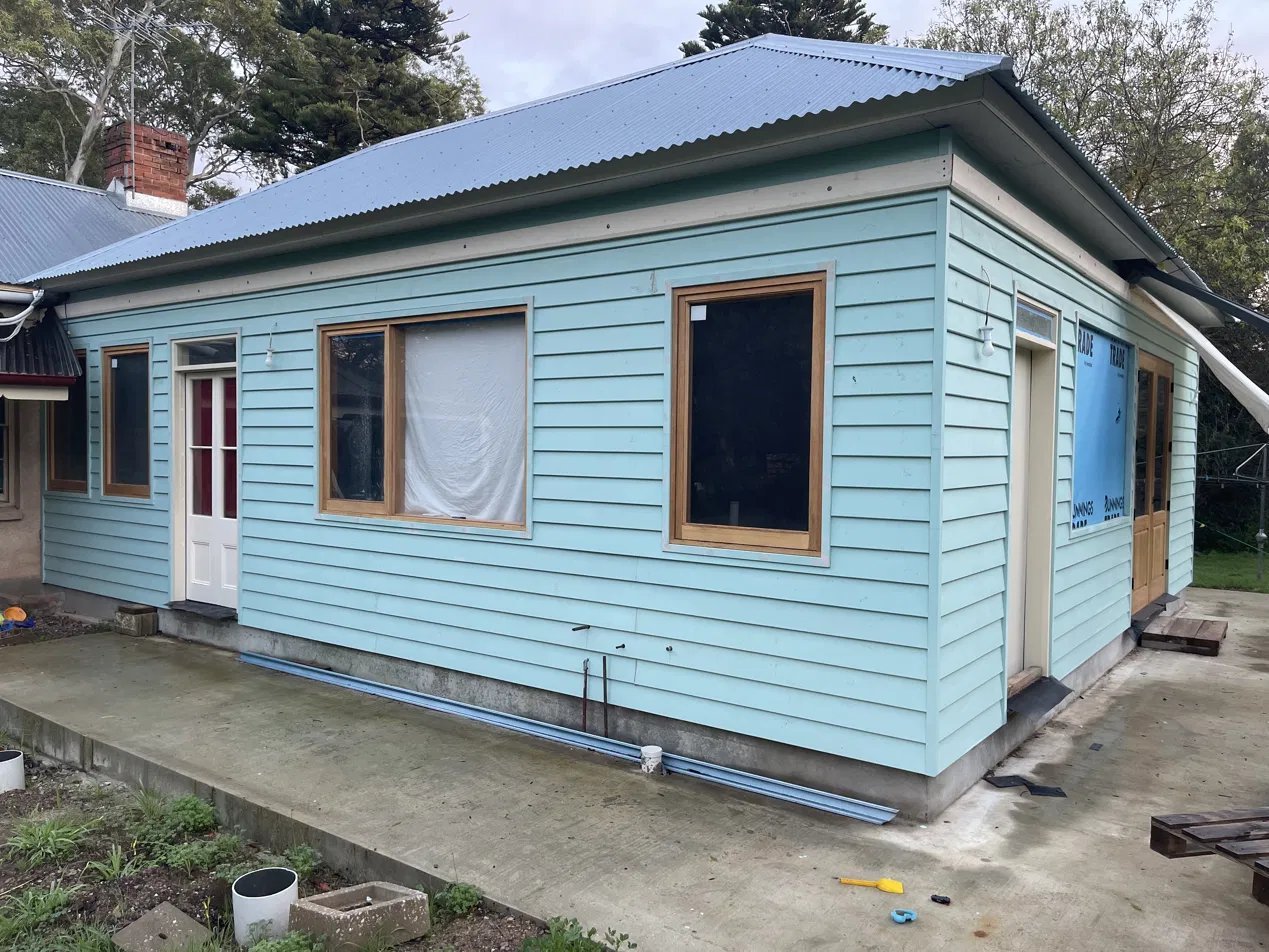 Timber-framed casement windows and entry door on a weatherboard home renovation